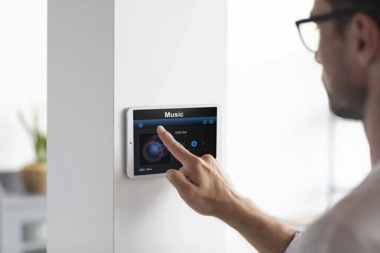 Ein Mann bedient ein an der Wand hängendes Touchdisplay zur Steuerung der Musik im Raum