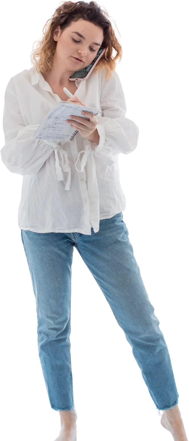 Young woman talking on the phone and writing down notes at the same time, holding the cell phone between her ear and shoulder