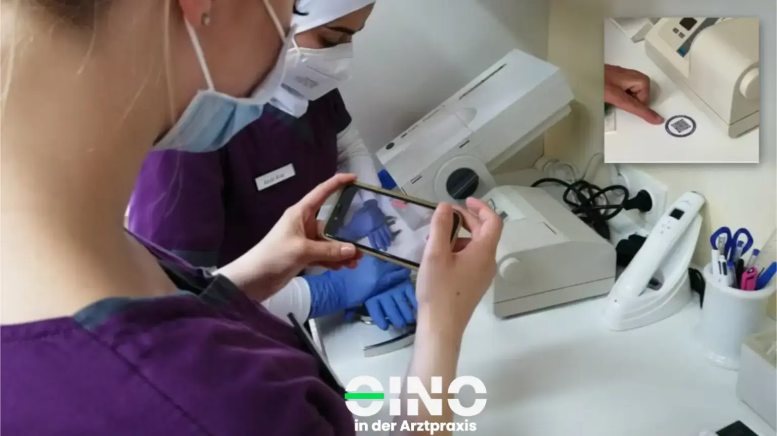 Zwei ZFAs stehen am Tisch und scannen mit dem Handy einen QR-Code
